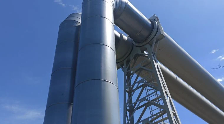 Close-up of large industrial steel pipes under a clear blue sky, showcasing engineering architecture