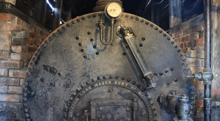 Rustic industrial boiler with intricate metalwork and brick surroundings in Marston, England