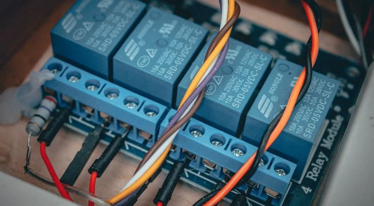 Blue relay modules with colorful wires connected on an electronic board
