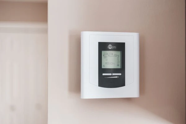Close-up of a modern digital thermostat mounted on a wall, displaying temperature settings in Celsius