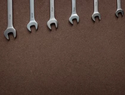 Top view of wrenches lined up on a textured brown surface, showcasing sizes