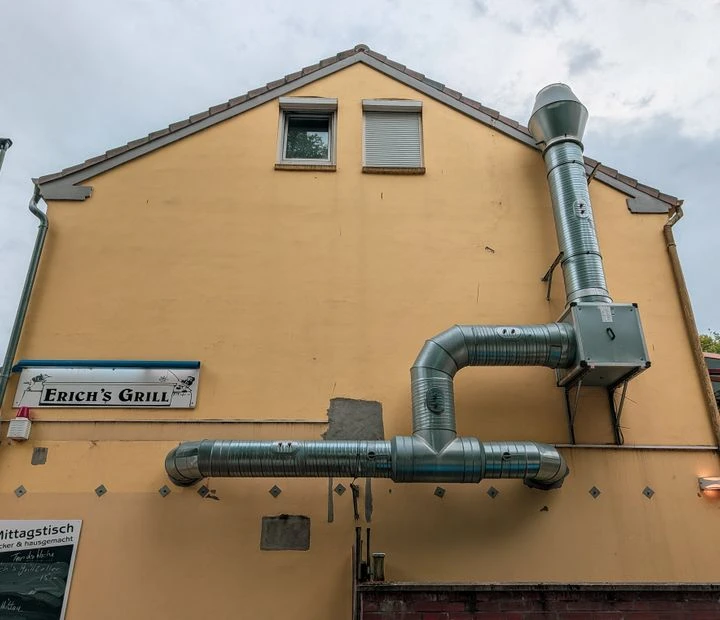 Image of a restaurant wall with prominent metal ventilation ducts and exterior sign